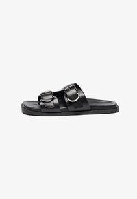Sandalias planas negras con dos correas ajustables y hebillas plateadas, una suela plana y un acabado mate suave.