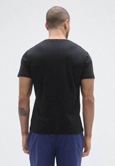 Črna bombažna majica s kratkimi rokavi, okroglim izrezom in osnovnim dizajnom. Prilegajoč kroj, minimalni šivi in gladka tekstura.