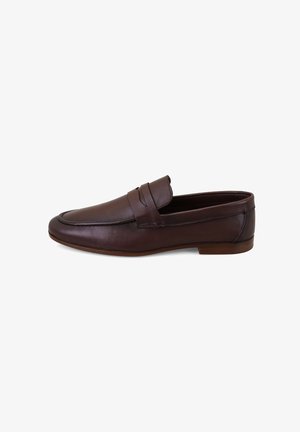Zapato tipo mocasín penny de cuero marrón oscuro con tacón bajo y puntera redondeada, mostrado desde el lado exterior sobre un fondo blanco.