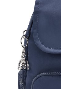 Navy nylon backpack features a zippered pocket and a silver robotic keychain attached to a metal loop with a glossy finish.
