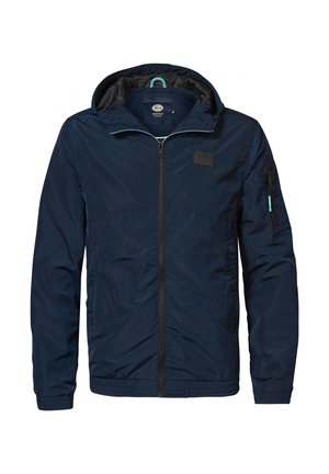 Marineblå letvægtsjakke med hætte, der har fuld lynlås og elastiske manchetter. Inkluderer et patch-logo og lynlåslomme på siden.