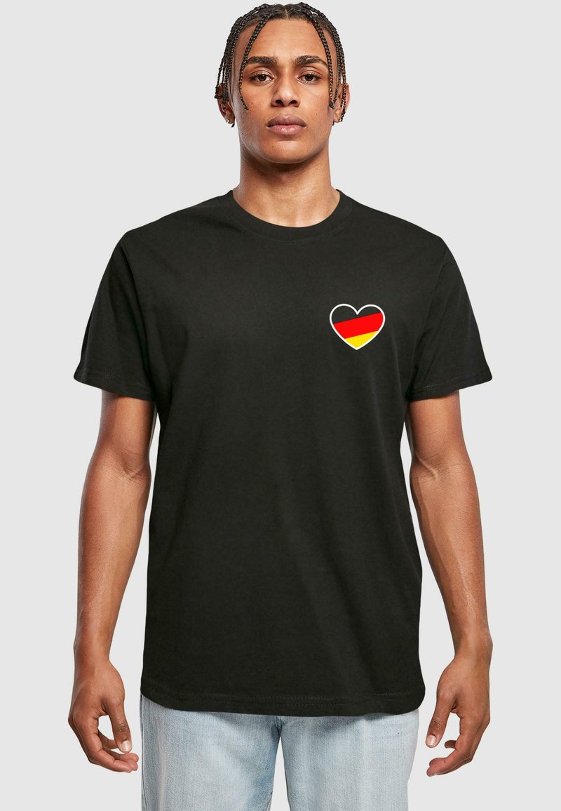 Schwarzes Baumwoll-T-Shirt mit einem Herzdesign, das eine rot-schwarz-gelbe Flagge enthält. Kurze Ärmel, Rundhalsausschnitt, lockere Passform.