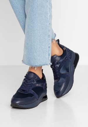 Granatowe buty sportowe wykonane z materiałów skórzanych i zamszowych. Cechy to perforowane akcenty, okrągły czubek oraz gruba podeszwa. Model ze sznurowaniem.