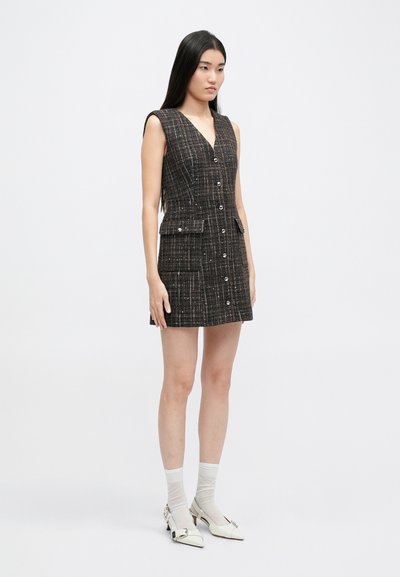 Vestido mini sin mangas en tweed negro con hilos multicolores, con botones delanteros, dos bolsillos y un corte entallado.