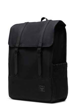Black backpack with a rectangular shape, made of durable fabric. Features adjustable straps, a top flap, and a side pocket. Logo tag visible.