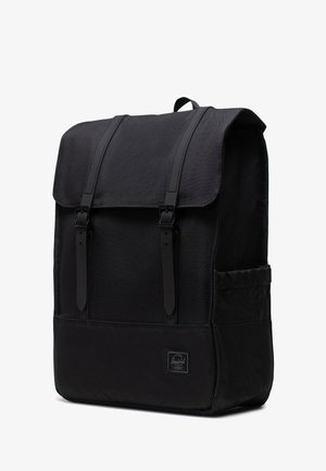 Musta reppu suorakulmaisen muotoisena, valmistettu kestävästä kankaasta. Varustettu säädettävillä kantohihnoilla, yläkannella ja sivutaskulla. Logo-tunnus näkyvissä.