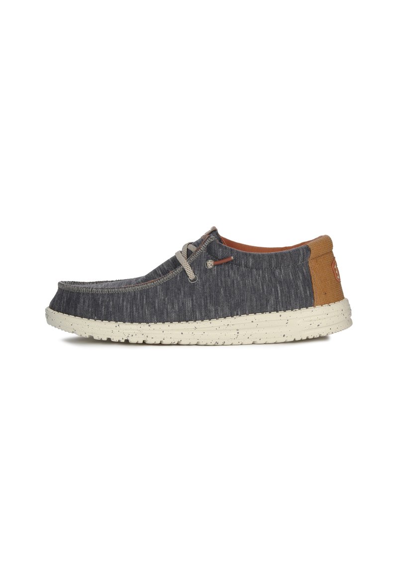 Scarpa in tessuto grigia con suola maculata beige, dettagli in pizzo e una piccola patches di pelle marrone sul tallone. Design minimalista, piatto con punta arrotondata.