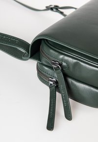 Borsa a tracolla verde in pelle con due scomparti con cerniera, superficie liscia e tirazip coordinati per un aspetto coeso.