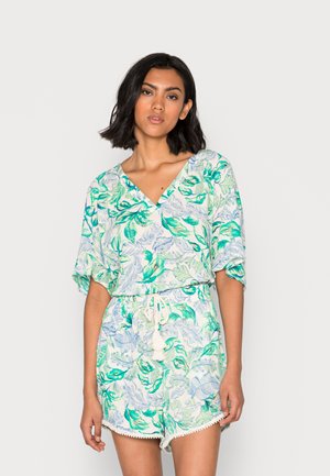 Macacão com estampa floral e mangas curtas, apresentando folhas azuis e verdes sobre um fundo claro, cintura ajustada e detalhes em laços de franjas.
