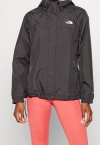 Black waterproof jacket with a hood, featuring elastic cuffs and a drawstring hem, brand logo on the chest, lightweight design.