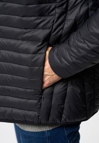 Schwarze Daunenjacke mit horizontalem Steppmuster, seitlichem Reißverschlusstaschen und kontrastierenden Bündchen. Weicher, glatter Stoff mit einem eleganten Aussehen.