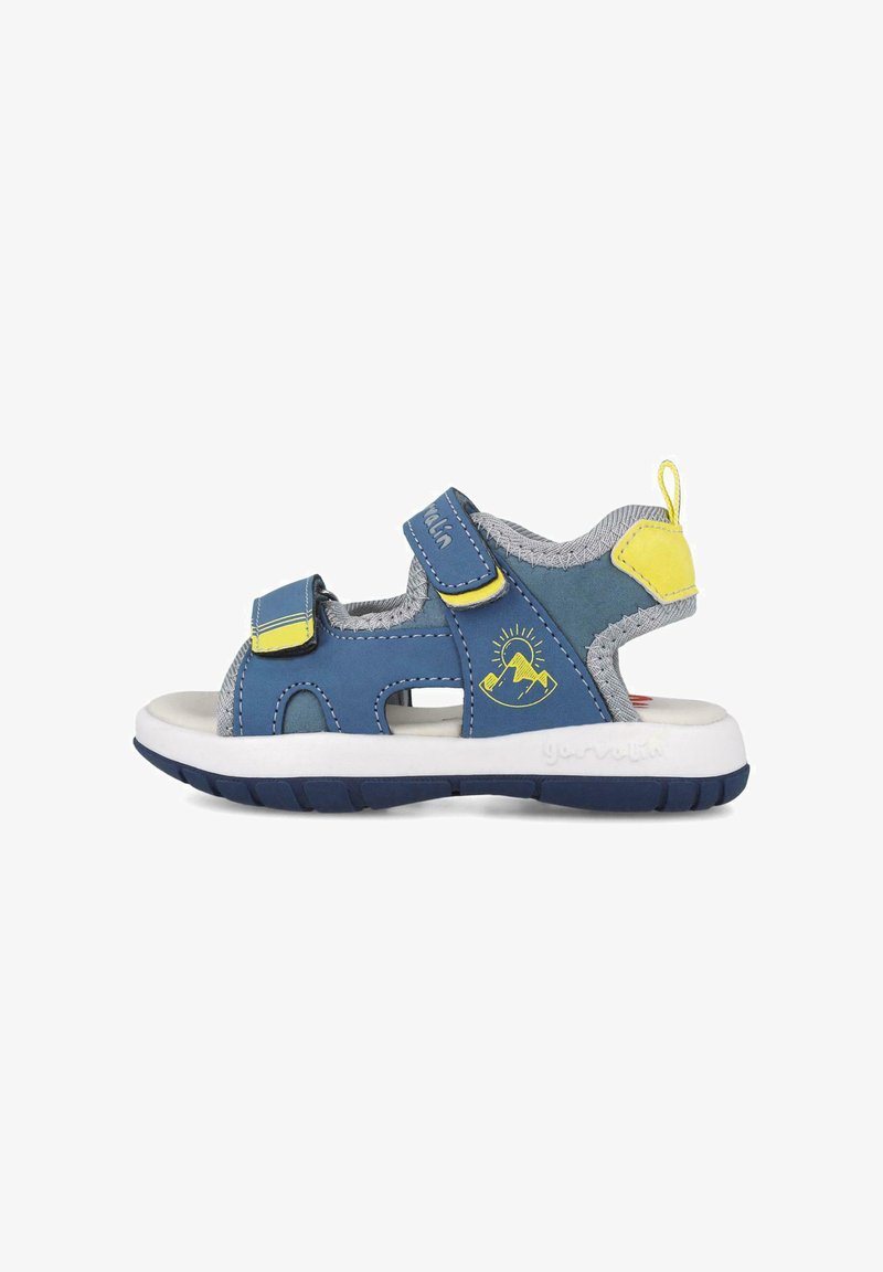 Sandal infantil sintético azul con acentos grises, doble correa de Velcro, punta abierta y suela de goma blanca. Presenta un gráfico de montaña amarilla y una pestaña de agarre.