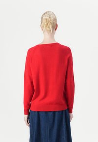 Red knitted sweater with a crew neckline, ribbed cuffs and hem, and a relaxed fit. The back features seamless raglan shoulder design.