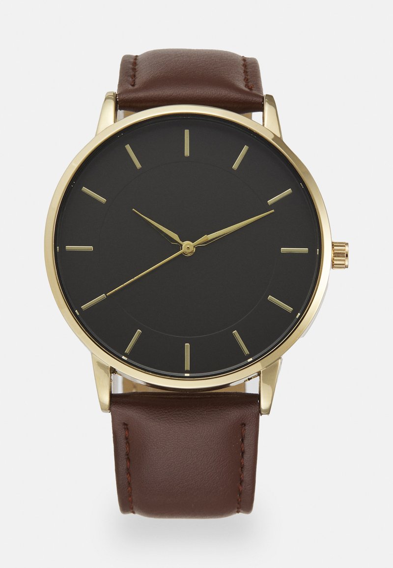 Round black watch with a gold-tone case, gold hands and markers, and a brown leather strap. Minimalist design with a smooth dial.