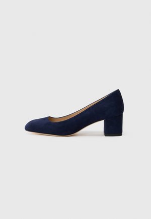 Zapato de tacón de ante azul marino con punta afilada y tacón bloque de altura media. Textura suave con un ligero brillo y un pequeño corte en la parte delantera.