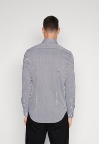 Camicia a maniche lunghe con sottili righe blu e bianche, colletto classico e orlo appuntito, realizzata in leggero tessuto di cotone.