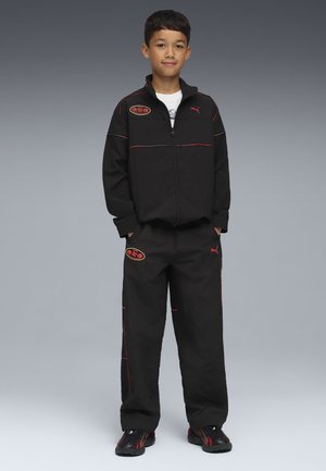 Svart träningsoverall med röda accenter, bestående av en jacka med dragkedja och lösa byxor. Inkluderar Puma-logotyp och en rund logotyp på jackan.