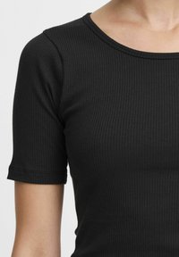 Top corto a maniche corte nero con scollatura tonda, caratterizzato da una texture sottile e un design aderente, che mette in risalto l'elasticità del tessuto.