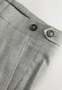 Grau karierte Hose aus strukturiertem Stoff, mit zwei schwarzen Knöpfen und einem Reißverschluss, im klassischen Schnitt und mit taillierten Fronttaschen.