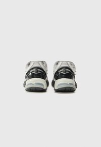 Baskets de sport noires et grises avec une tige en mesh, un col rembourré et un design de semelle distinctif avec des accents transparents. Support arrière texturé.
