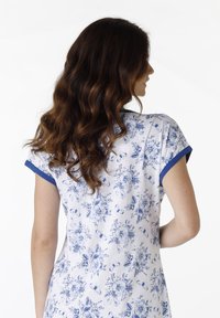 Camicetta da notte con motivo floreale in bianco e blu, con maniche corte arrotolate e una vestibilità rilassata. Tessuto morbido con leggera trama.