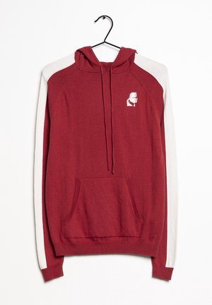 Rote Kapuze mit weißen Raglanärmeln, einer Fronttasche und einem kleinen Logo auf der Brust. Hergestellt aus einem weichen, strukturierten Stoff.
