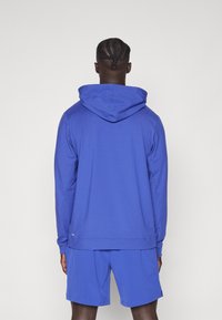 Koninklijk blauwe hoodie met een trekkoordkap, lange mouwen en een kangoeroezak, gecombineerd met bijpassende shorts. Soepele stoftextuur.