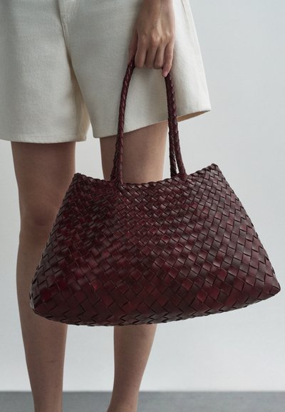 Auklas ādas toņs tumši bordo, ar divām rokturiem, plašu formu un teksturētu virsmu, piemērots ikdienas lietošanai.