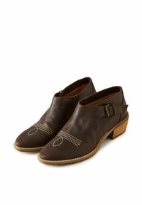 Botas de cuero marrón hasta el tobillo con punta afilada, hebilla lateral, tacón de madera y detalle de costura blanca en la parte superior.