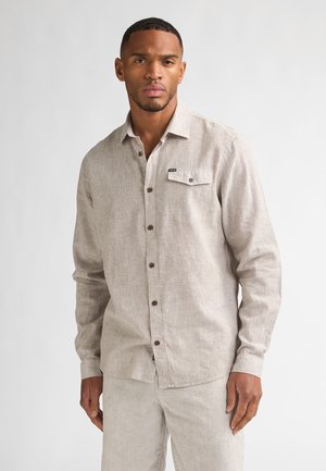 Chemise à rayures beige et crème avec manches longues, une poche poitrine et des boutons marron. Fabriquée en tissu texturé.