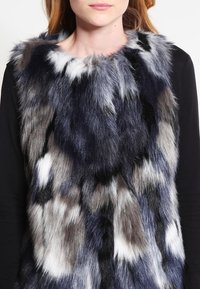 Faux furväst med ett flerfärgat mönster i gråtoner och svart, med en mjuk textur och rundad halsringning.