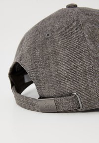 Gray fabric cap with a textured finish, adjustable strap at the back, and a metal fastener featuring a circular logo detail.