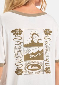 Korte mouwen, witte T-shirt met een lichtbruine grafische print van golven, bloemen en surf- gerelateerde beelden. Zacht katoenmateriaal.