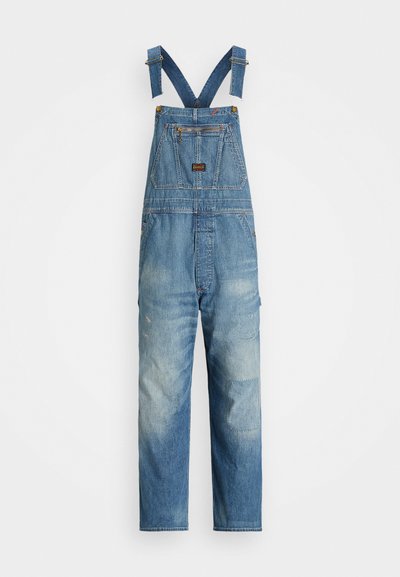 Džinsu kopas ar regulējamām zilām plecu siksnām, priekšējo kabatu un izbalējušu zilu krāsu ar pleķu detaļām uz kājām.