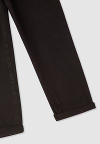 Czarne dżinsy o gładkiej fakturze, lekko zwężane nogawki i podwinięte mankiety. Posiadają kontrastowe szwy wzdłuż szwów.