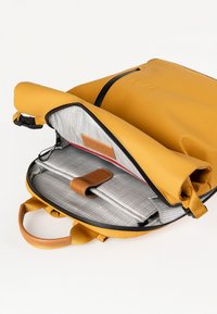 Zaino impermeabile giallo con interno grigio, dotato di scomparto per laptop, dettagli in pelle e chiusura a zip. Il design include una maniglia superiore.