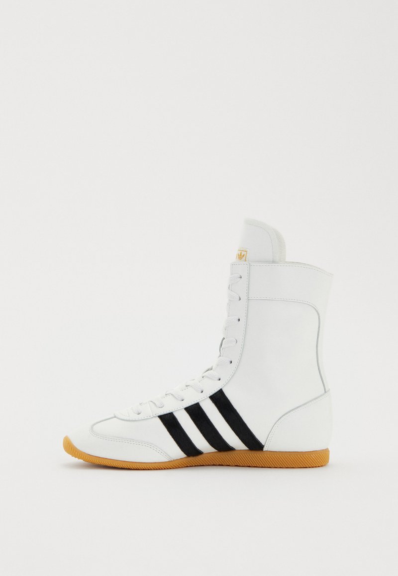 Weißer High-Top-Sportschuh mit schwarzen Streifen, glattem synthetischen Obermaterial, Gummisohle und gepolstertem Kragen. Mit Schnürverschluss und strukturiertem Design.