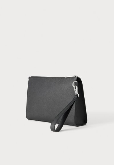 Pochette bracelet rectangulaire noire avec surface texturée, fermeture éclair argentée et sangle détachable sur fond gris clair.