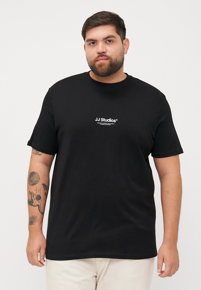 Schwarz T-Shirt mit kurzen Ärmeln, das ein weißes "JJ Studios"-Logo aufweist. Glattes Material und entspannte Passform. Einfaches Design ohne zusätzliche Muster oder Akzente.