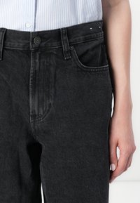 Dark grey denim jeans with a classic fit, featuring a single front pocket, metal button closure, and subtle stitching details.