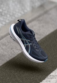 Morska tekaška čevlja z zračnim mrežastim zgornjim delom, belim podplatom, svetlo modrimi akcenti in teksturiranim podplatom za oprijem. Lahka in fleksibilna zasnova.