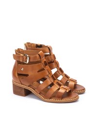 Sandali con tacco in pelle color cuoio, dotati di più cinturini orizzontali, chiusura laterale con zip e tacco a blocco. Finitura liscia, dettagli cuciti attorno alla suola.