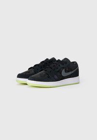 Crne suede tenisice s bijelim srednjim dijelom i neon zelenim potplatom. Ima sivi Nike swoosh i crne vezice. Detalji teksturirane površine.