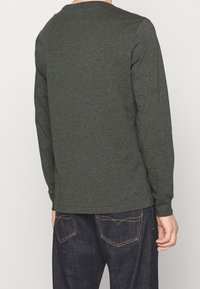 Långärmad skjorta i mörkgrön tyg med rund halsringning och avslappnad passform. Baksidan är slät med subtila sömnadsdetaljer.