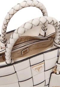 Borsa a tracolla bianca intrecciata con manici intrecciati, hardware dorato e molteplici scomparti interni. Presenta un rivestimento a fantasia e dettagli di marchio.