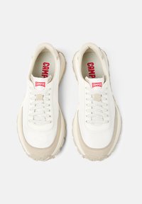 Sneakers bianchi in tela con accenti in suede beige, dotati di punta rotonda, suola testurizzata e etichetta rossa "CAMPER" sulla linguetta.