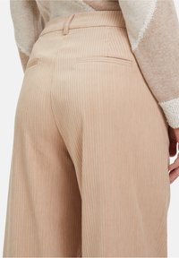 Beige geribde broeken met een hoge taille, zijzakken en een gladde textuur, met een stijlvolle pasvorm en subtiele verticale lijnen.