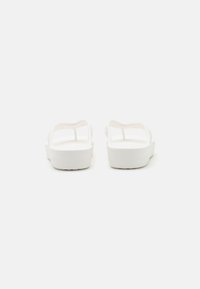 Sandales blanches à design ouvert, semelles plates et fonds texturés. Fabriquées en matériau en caoutchouc, elles possèdent des bretelles minimalistes et une finition lisse.