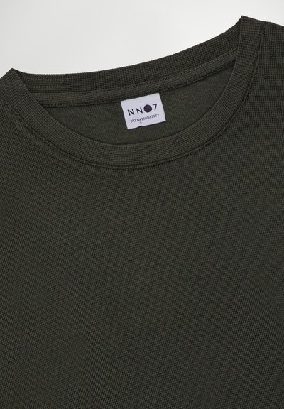 T-shirt en coton texturé vert foncé à col ras du cou avec une étiquette portant la mention "NN07 NO NATIONALITY". Il présente un col ribbed et un tissu tissé.