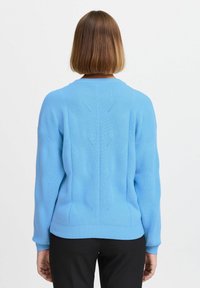 Maglione lavorato a maglia blu chiaro con polsini e orlo a coste, caratterizzato da un motivo testurizzato sul retro e un collo rotondo.
